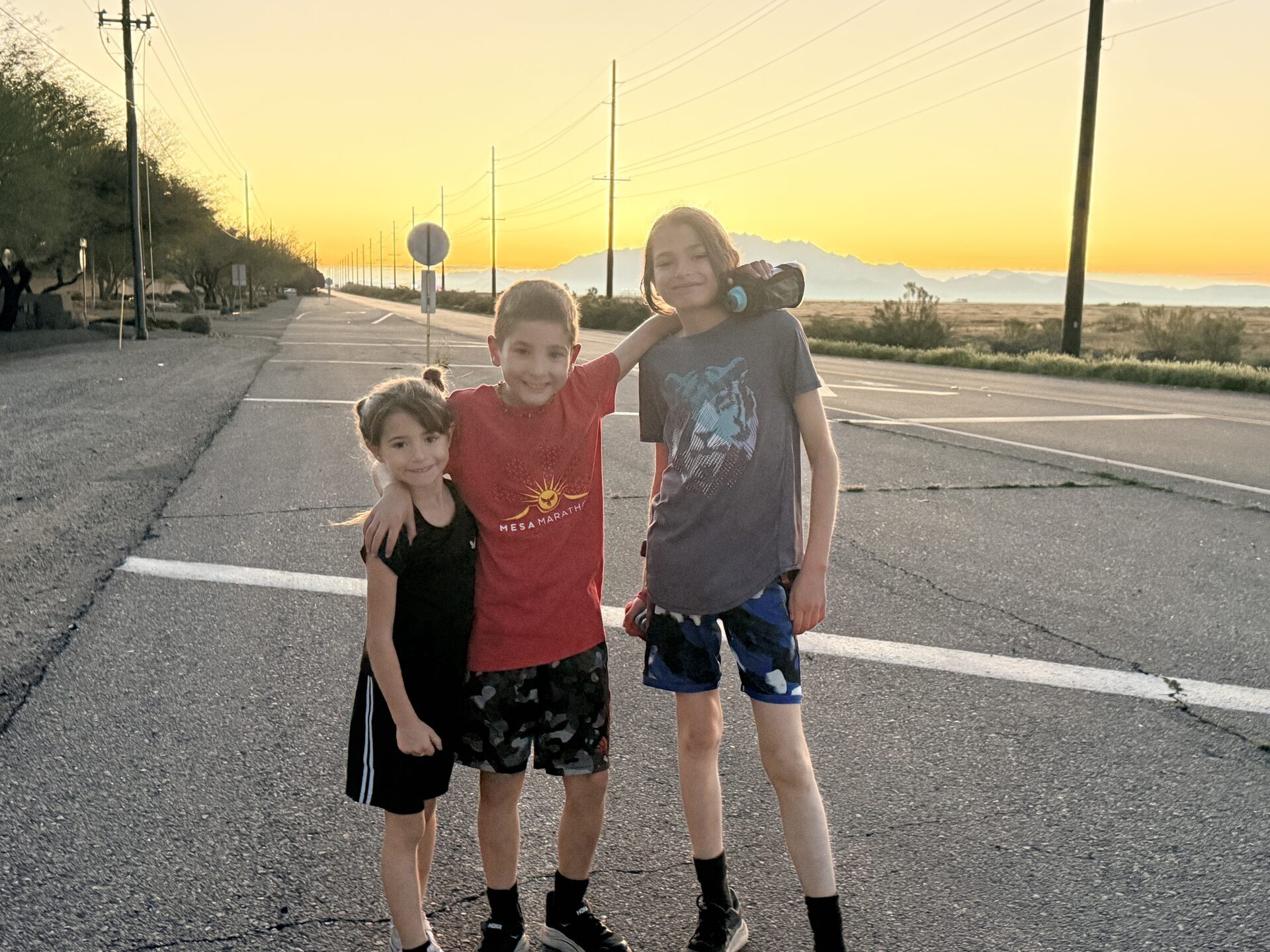Sage (6), Atlas (10), and Asa (12) on Hunt Highway as the sun rises over the Santan Mountains